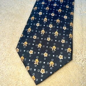Hermes 100% silk necktie. Black with gold flower pattern. 3.6” wide. 7904 MA.